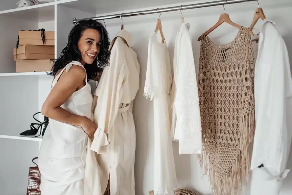 mulher sorridente junto ao guarda-roupa com peças de verão