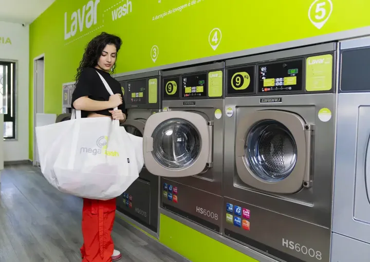 jovem com saco de roupa suja na lavandaria megawash