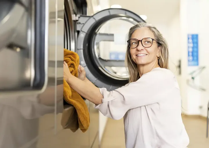 mulher a lavar têxteis-lar na máquina da lavandaria self-service