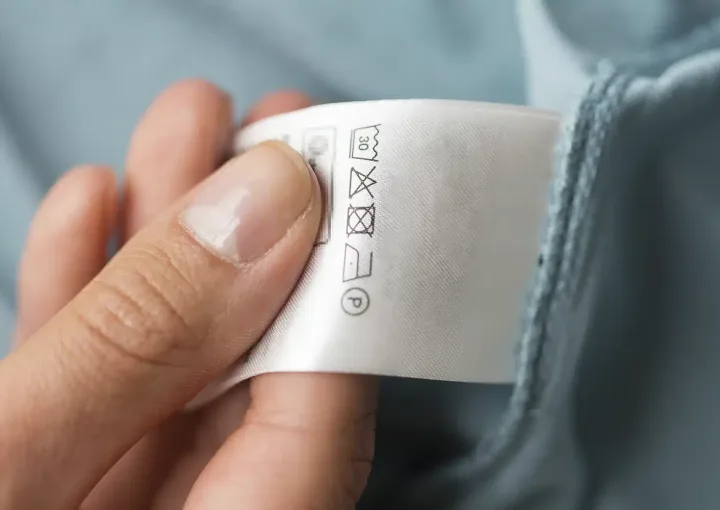 mão segura etiqueta da roupa com símbolos de secar roupa
